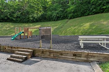a playground with a sign and a picnic table
